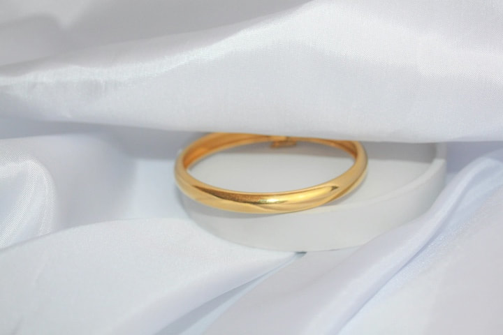 A gold wedding band on white silk